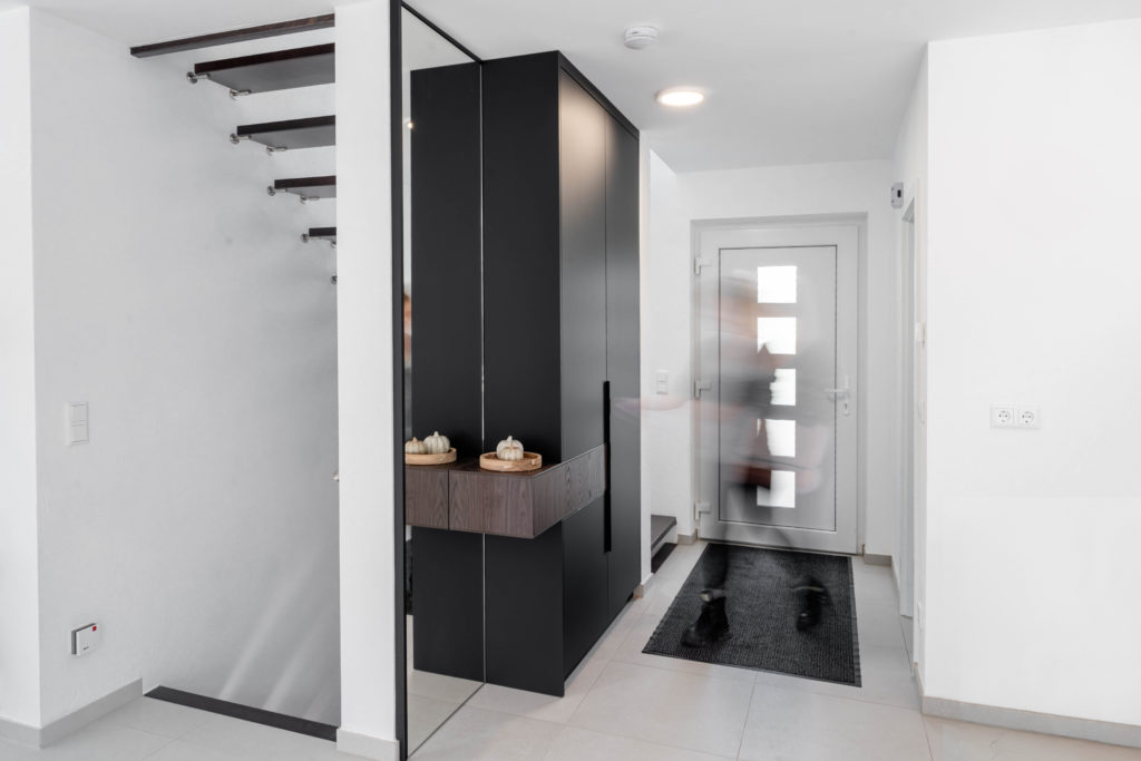 Modern hallway with custom-made wardrobe and mirror front, person in motion