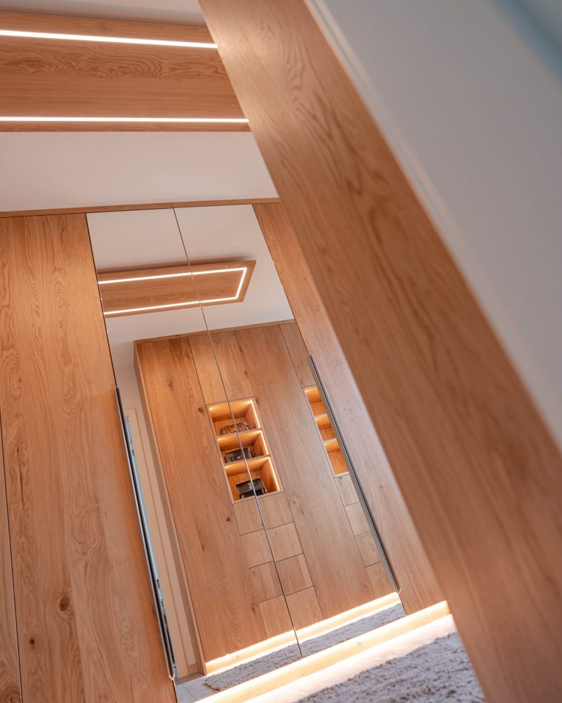 Custom-made dressing room with mirror front, wooden wardrobes and integrated lighting
