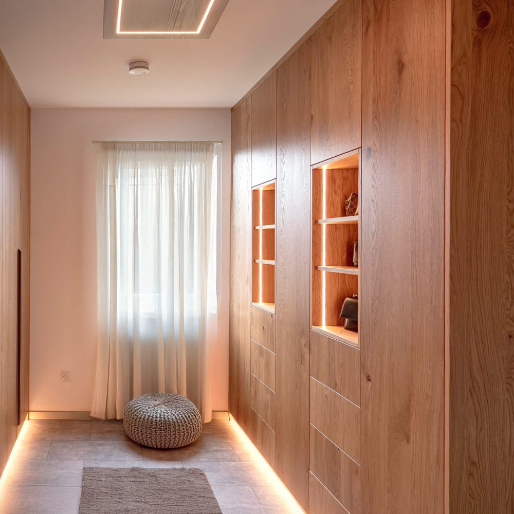 Custom-made wooden hallway cabinet with illuminated display cabinet compartments and integrated storage space