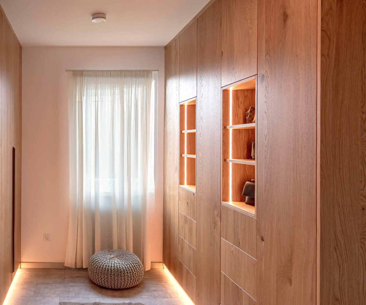 Custom-made wooden hallway cabinet with illuminated display cabinet compartments and integrated storage space