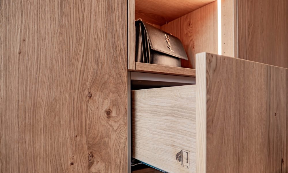 Detail eines maßgefertigten Holzschranks mit geöffneter Schublade und integrierter Beleuchtung