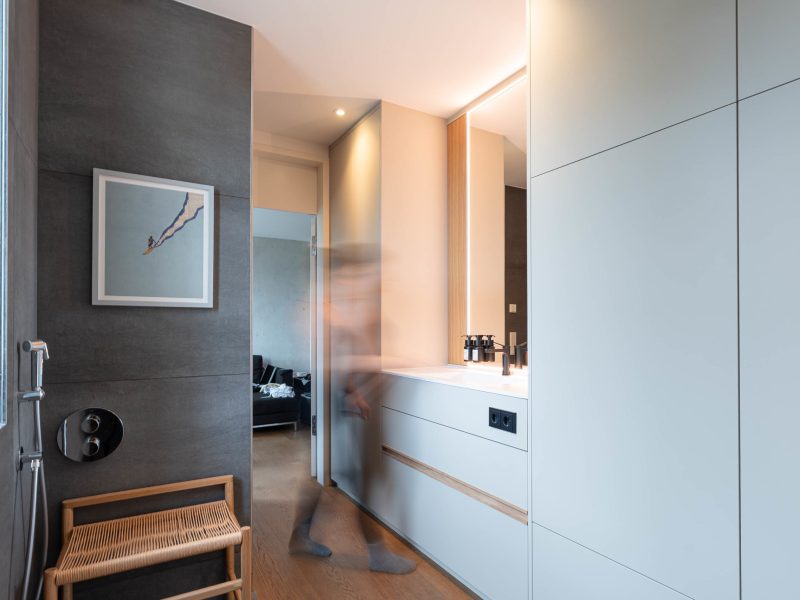 Modern bathroom with a custom-built cabinet and sink area; person in motion