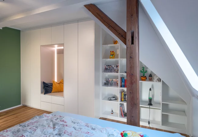 Sloping ceiling cabinet in matt white with seat inlay
