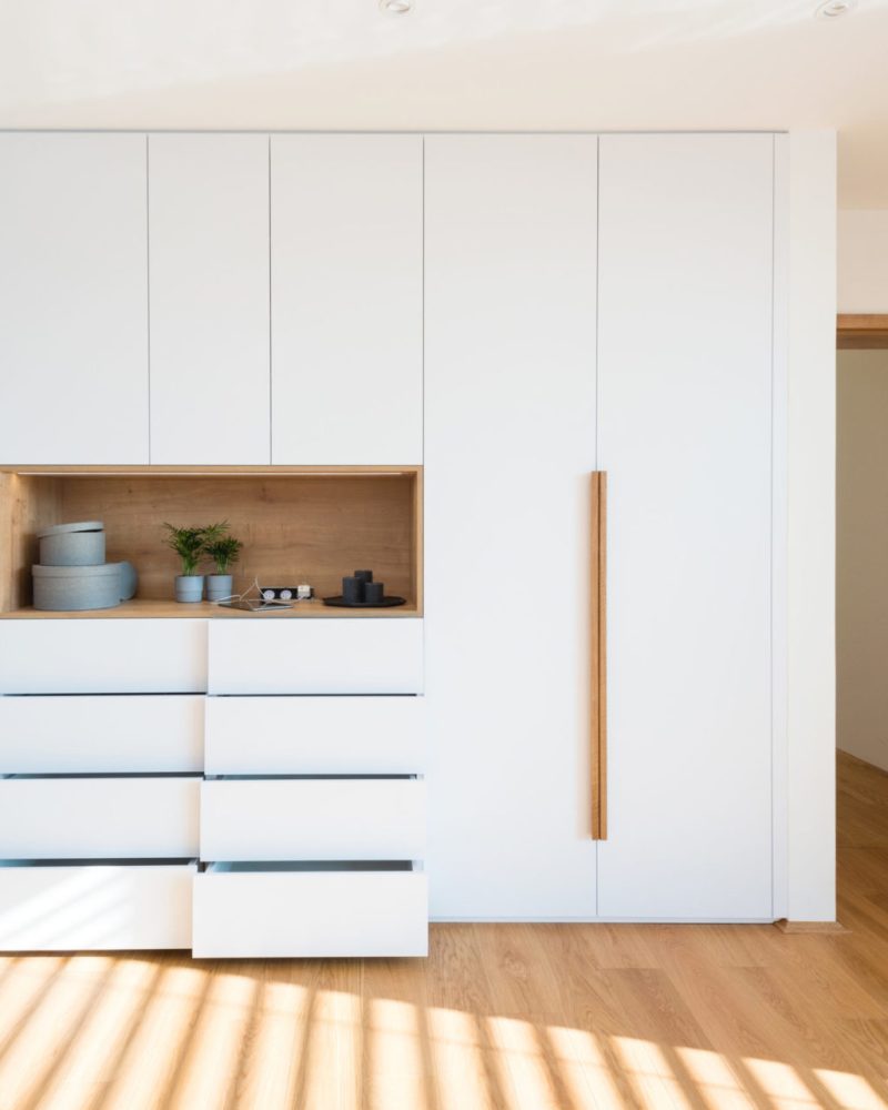White wooden wardrobe with open shelves in the bedroom of a modern home