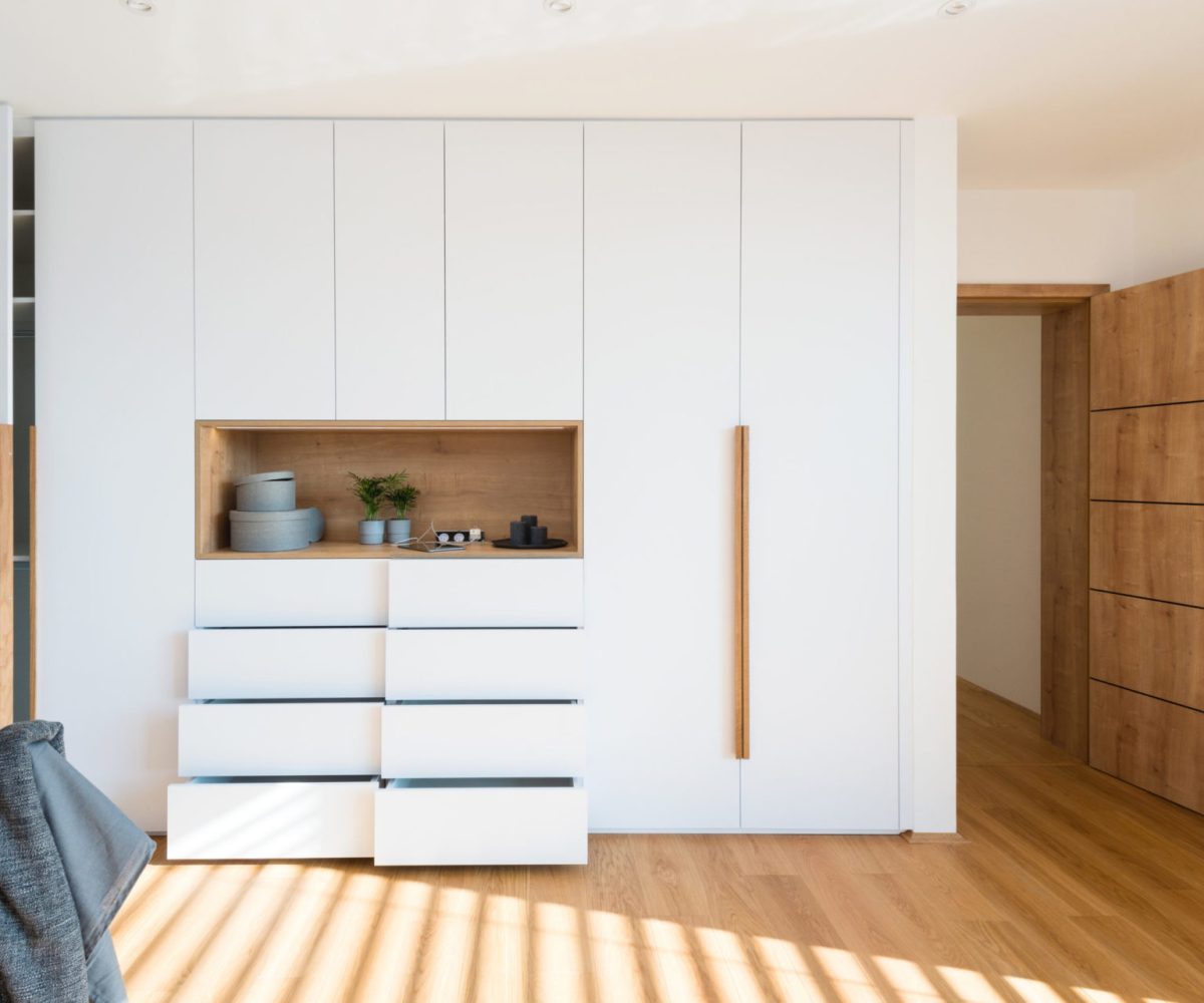 White wooden wardrobe with open shelves in the bedroom of a modern home