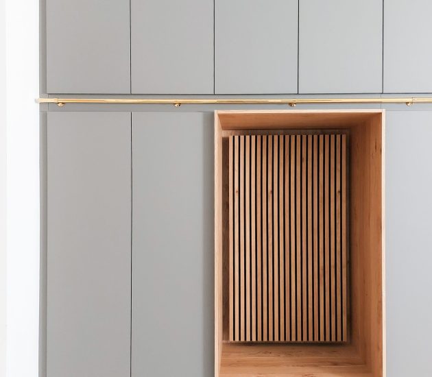 Grauer Einbauschrank mit Holzpaneelen und goldenem Akzent