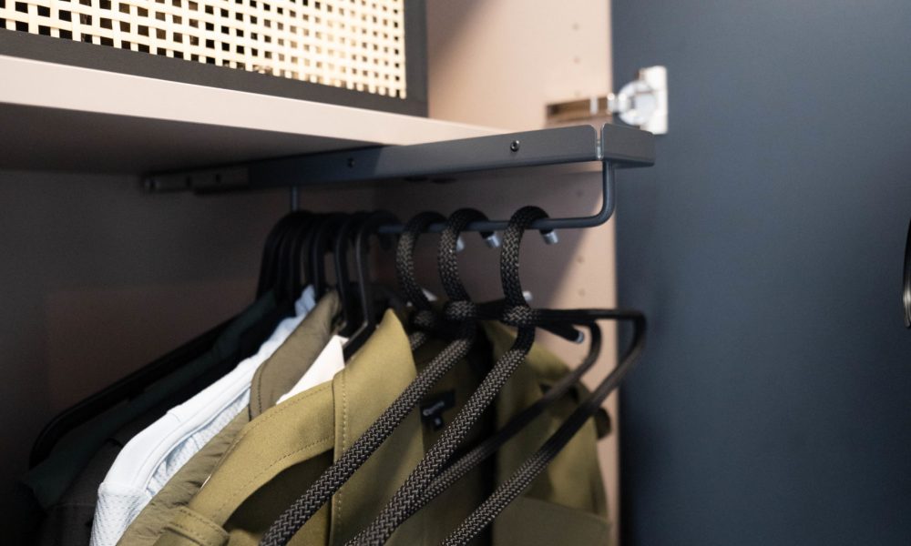 Detail einer maßgefertigten Garderobe mit Kleiderstange und aufgehängten Jacken