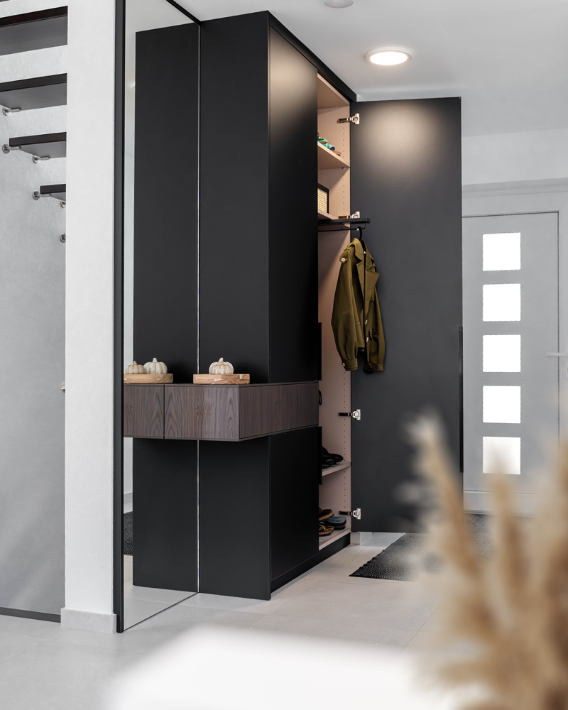 Made-to-measure wardrobe in the hallway with open wardrobe door, integrated chest of drawers and mirror