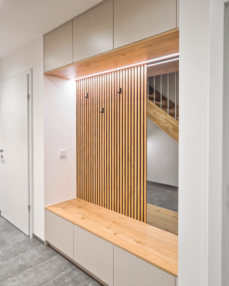 Custom-made wardrobe with slatted wall, integrated lighting and wooden bench seat