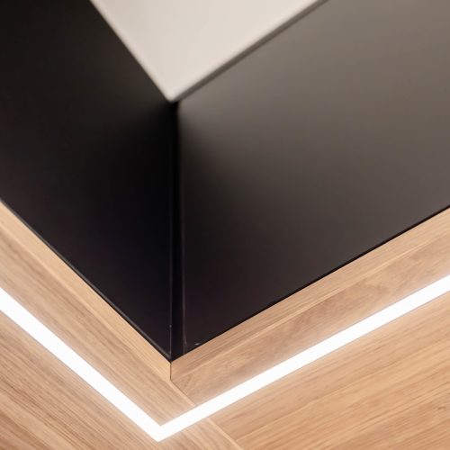 Matt black wardrobe with oak panels and LED lighting—view of the LED lighting from below