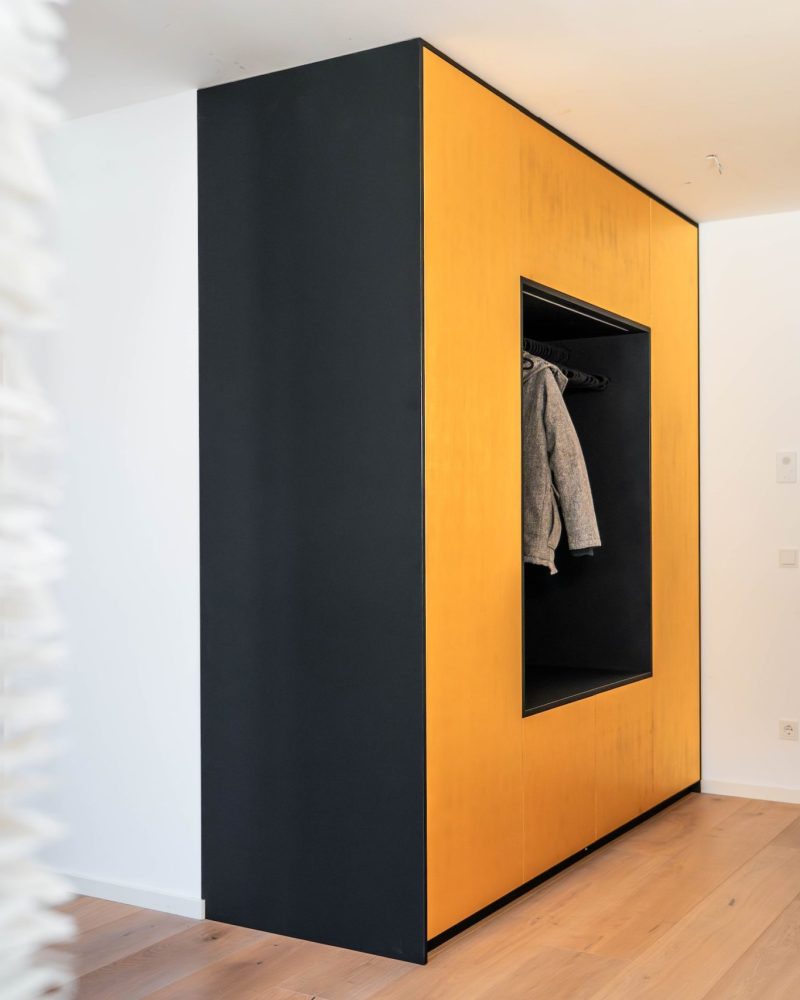 Wardrobe with seating niche in matt black with golden fronts