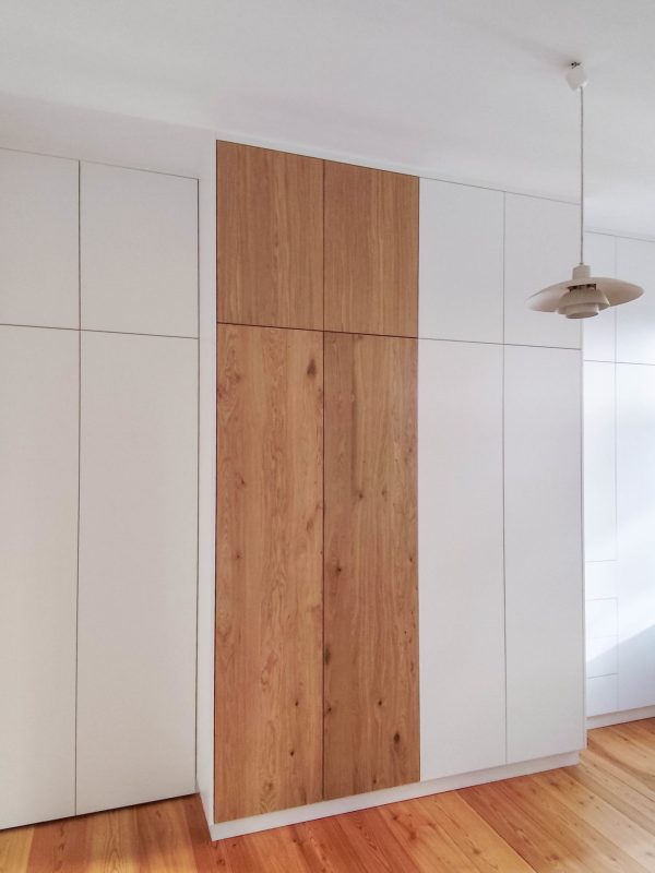 Custom-built built-in closet in white with a wooden front in the center of the bedroom