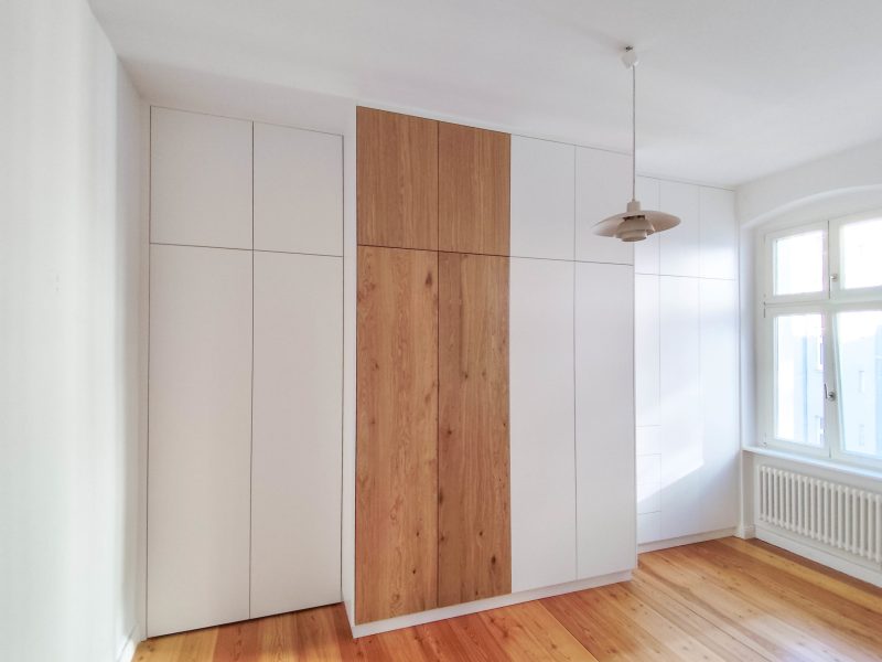Custom-built built-in closet in white with a wooden front in the center of the bedroom