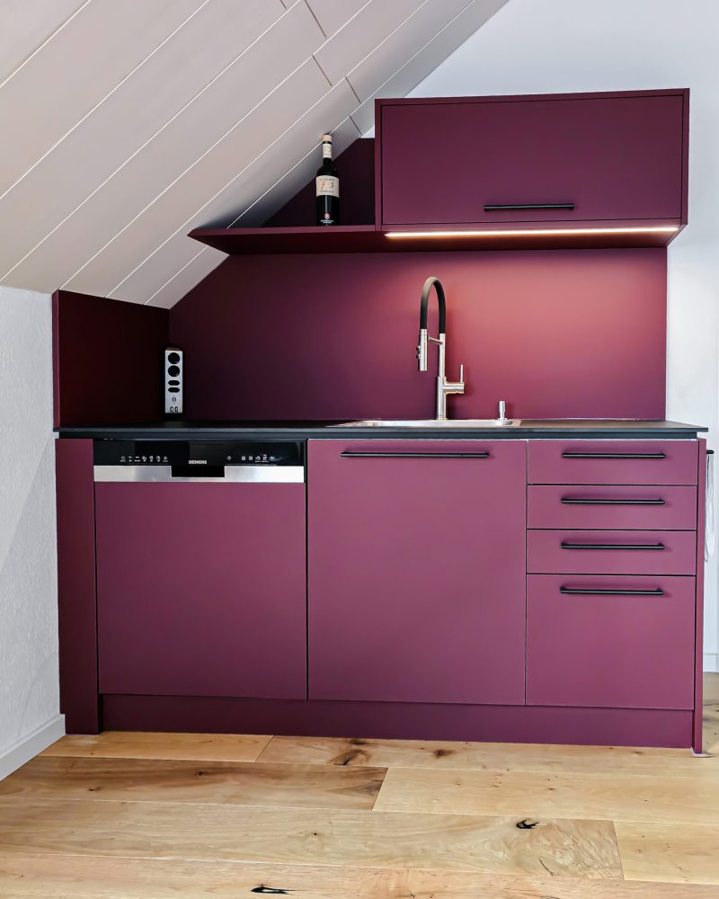 Burgundy kitchen unit under the sloping roof