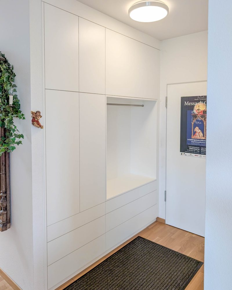 Custom-made wardrobe in white with open niche and integrated storage space in the hallway